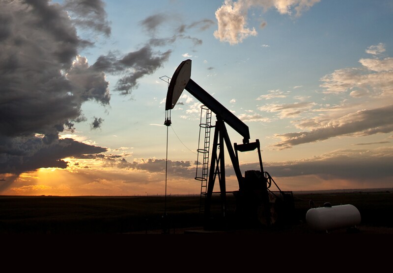 A pumpjack on the prairie. Alberta, Canada. Silhouette. Dramatic sunset sky. Copyspace.