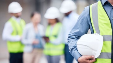 Shot of an unrecognizable architect holding a helmet at a building site