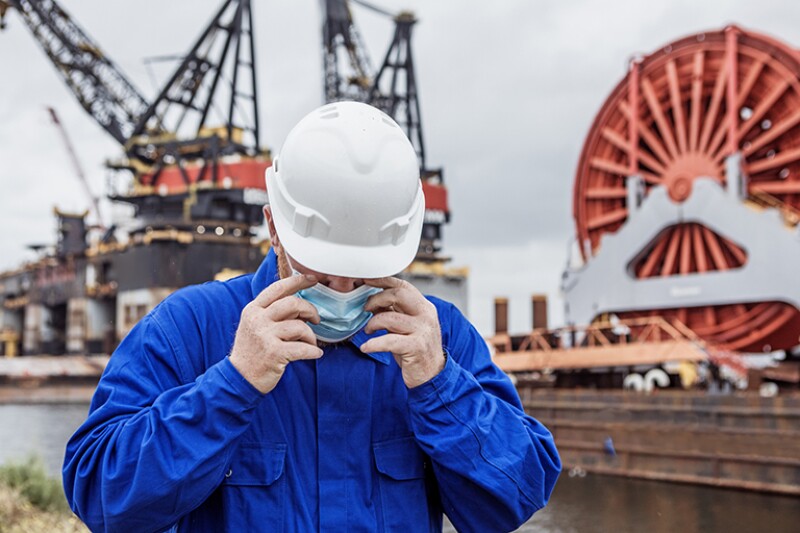 A male engineer at an oil and gas construction site wearing a covid mask