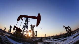 Oil field site, in the evening, oil pumps are running