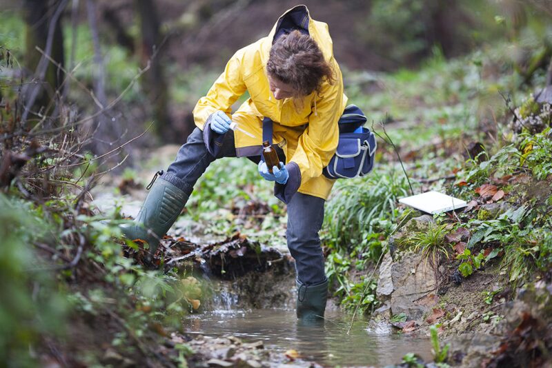 Worker testing water in a stream