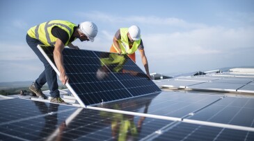 Two engineers installing solar panels on roof.