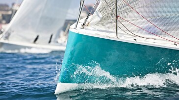 Front of a sailing boat in a regatta with waves hitting it
