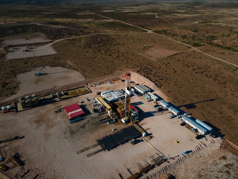 Captured from a drone's perspective, a stunning sunset illuminates the Permian Basin's fracking drilling oil rig, showcasing the complex industrial processes at work in the energy sector