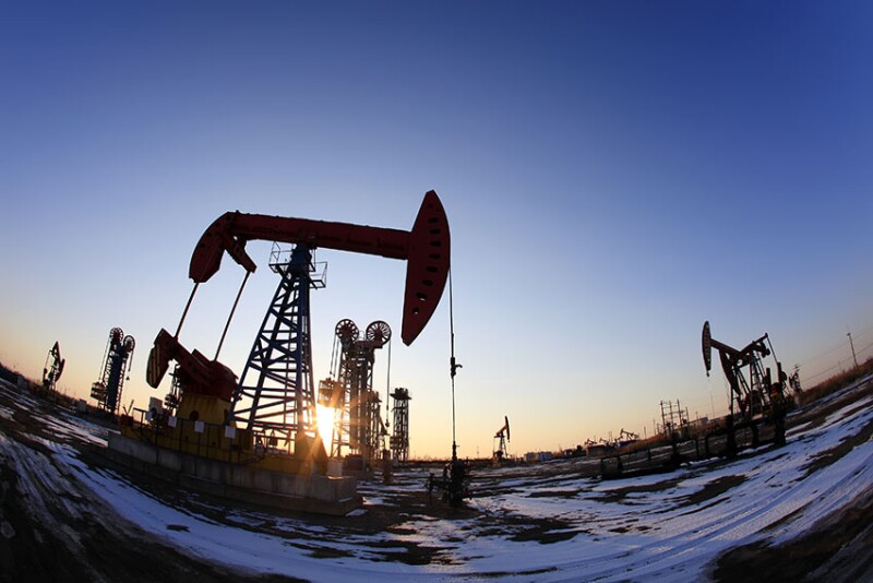Oil field site, in the evening, oil pumps are running