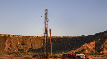 Workover rig working on a previously drilled well trying to restore production through repair in Western Oklahoma with sunset reflecting off red dirt Gloss Mountains