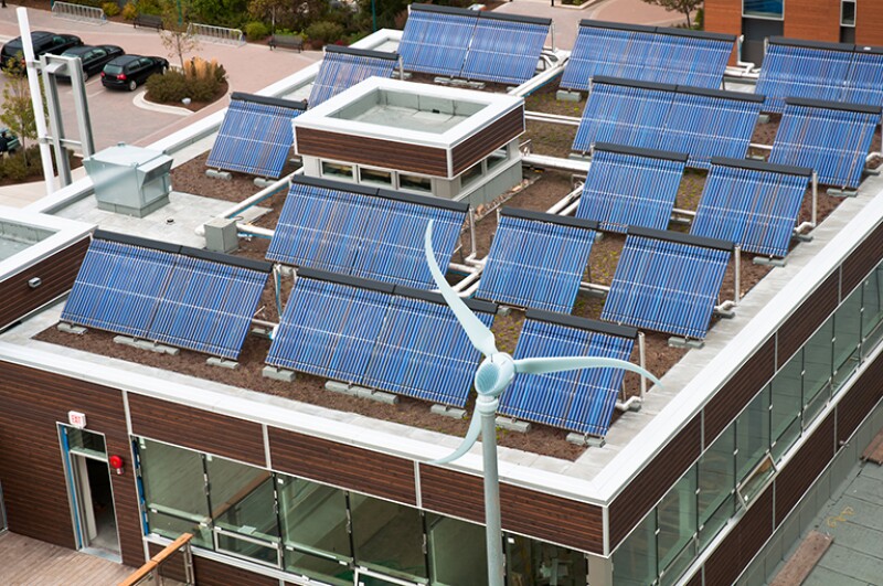 An array of solar panels on the roof of a small building in Halifax, Nova Scotia with a small wind turbine situated nearby.