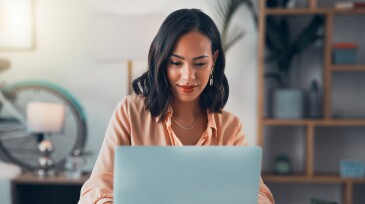 Woman working on laptop online, checking emails and planning on the internet while sitting in an office alone at work. Business woman, corporate professional or manager searching the internet