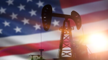 silhouette of oil drilling pump on background of united states flag.