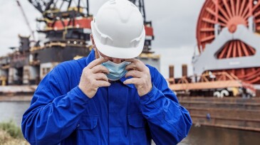 A male engineer at an oil and gas construction site wearing a covid mask
