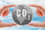 CO2 capture concept. Human hand holding CO2 in globe map on blue sky. Carbon capture and storage technology concept. Greenhouse gas. Carbon dioxide gas global air climate pollution. Environment issue.