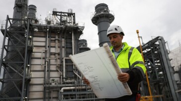 System  engineer with glow green safety jacket holds blueprint drawing at Thermal  Power plant power manufacturing site