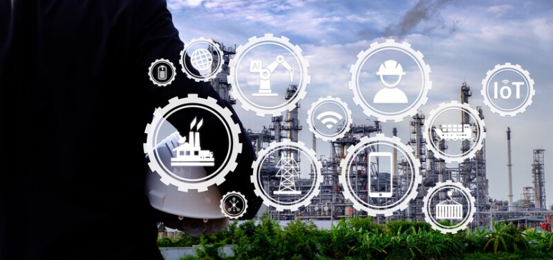 The engineer is holding a helmet with large industry background.