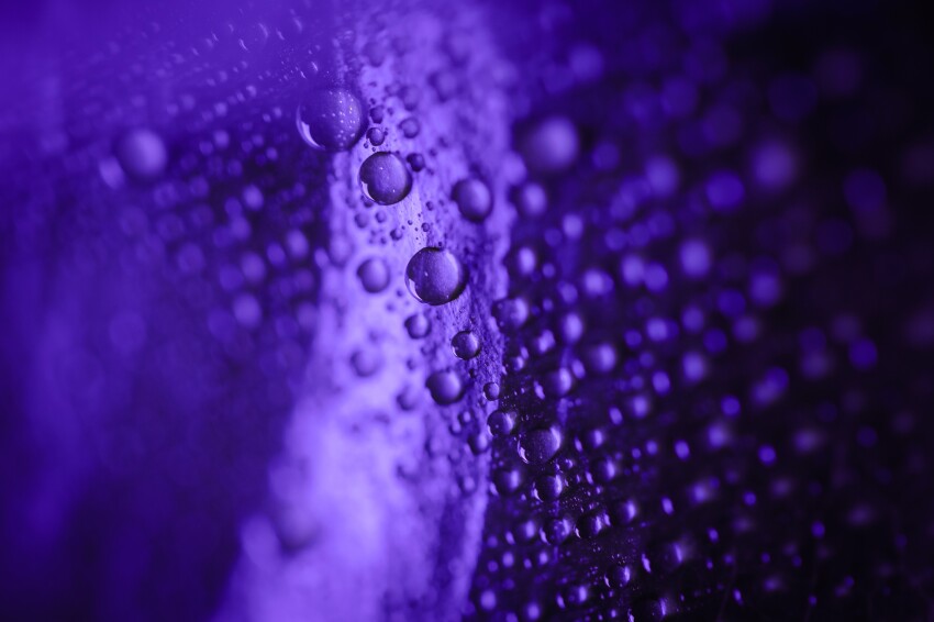 Shot of wet purple surface with colorful glistering water drops