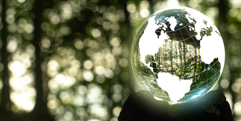 Focus on taking care of nature and the climate shown with a globe around  a crystal ball with nature reflected and inside the ball