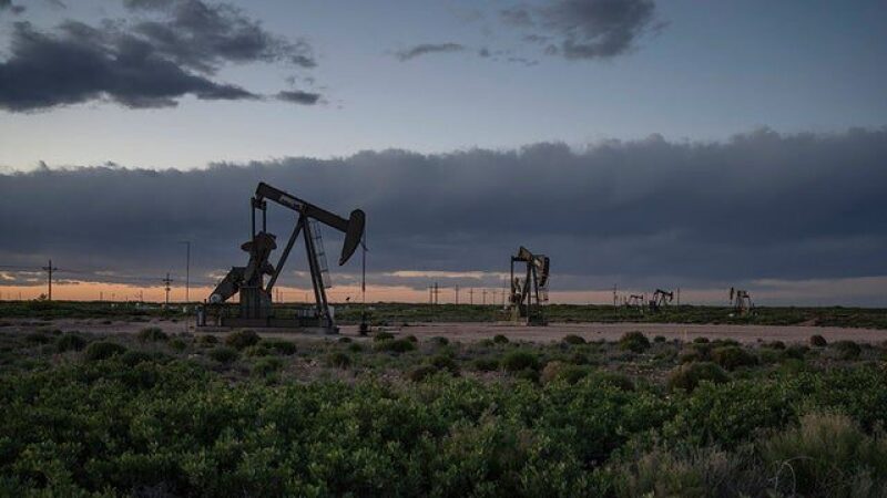 Line of pump jacks with storm clouds in the background