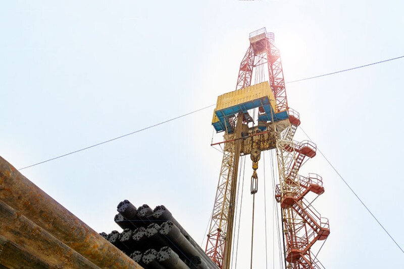 Oil and Gas Drilling Rig onshore dessert with dramatic cloudscape. Oil drilling rig operation on the oil platform in oil and gas industry. Land drilling rig blue sky.
