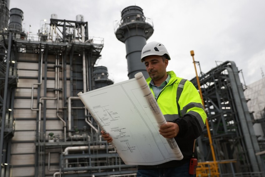 System  engineer with glow green safety jacket holds blueprint drawing at Thermal  Power plant power manufacturing site
