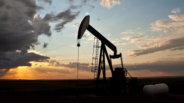 A pumpjack on the prairie. Alberta, Canada. Silhouette. Dramatic sunset sky. Copyspace.