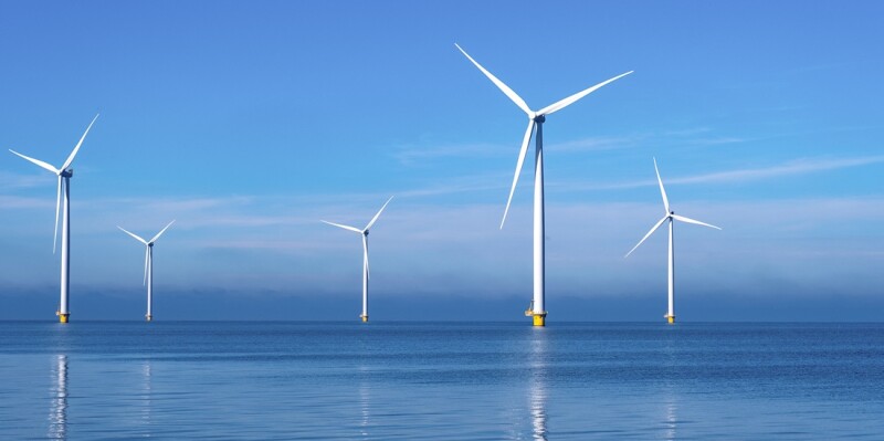 offshore windmill park with clouds and a blue sky