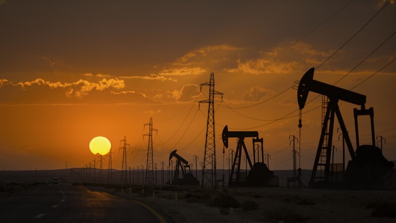 Oil wells and power lines on the side of the highway.
