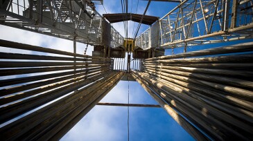 View looking upward at a drilling rig with a full loaded pipe rack