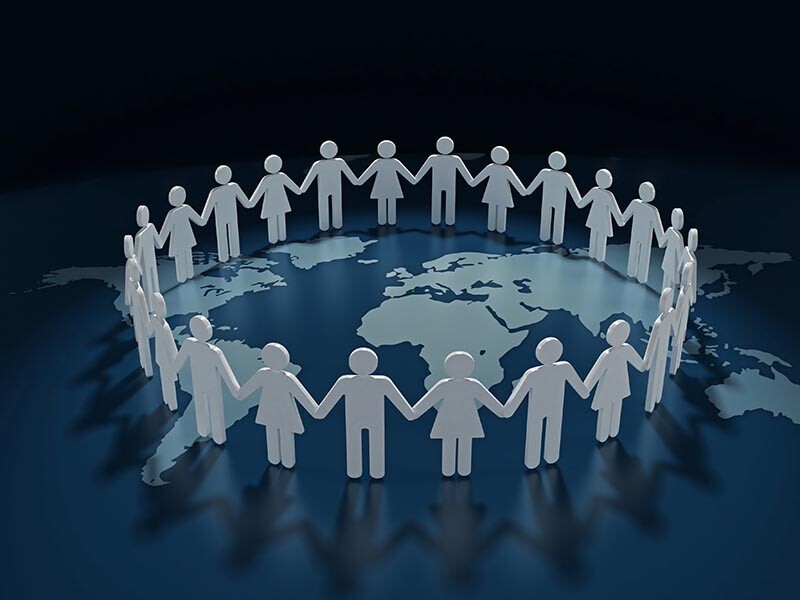 People holding hands in a circle on a world map