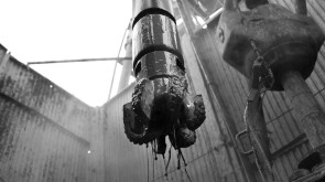 Drilling bit and positive displacement motor in front of drilling rig in black & white