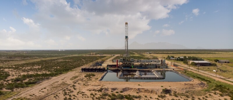 Fracking Drilling Rig Evening Shot under dramatic Sky in West Texas with Settling Ponds on the Prairie