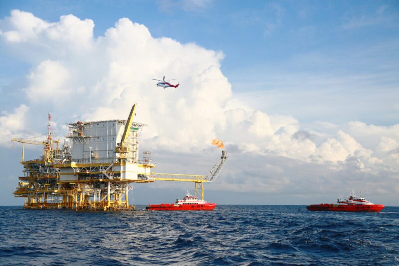 Supply boats and helicopter approaching an offshore platform