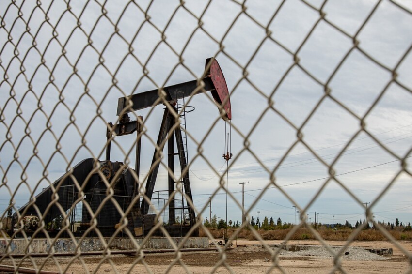Oil Pump in Cloudy Rough Weather with Chain Link Fence