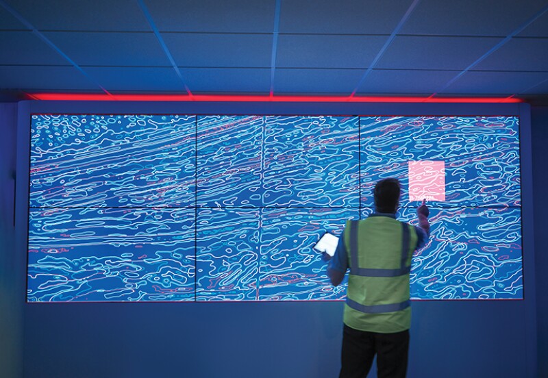 Geologist studying graphical display of oil and gas bearing rock on screens