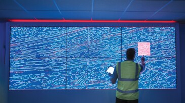 Geologist studying graphical display of oil and gas bearing rock on screens
