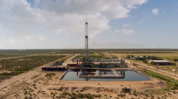 Fracking Drilling Rig Evening Shot under dramatic Sky in West Texas with Settling Ponds on the Prairie