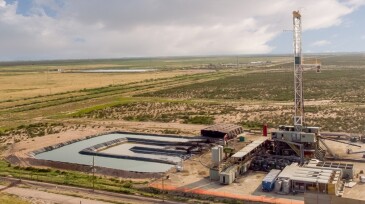 Fracking Drilling Rig Evening Shot under dramatic Sky in West Texas with Settling Ponds on the Prairie