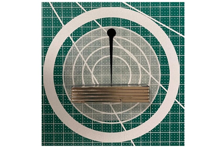 Fig. 1—Ferrofluid drop (black) attracted to magnets (gray) 50 mm away.