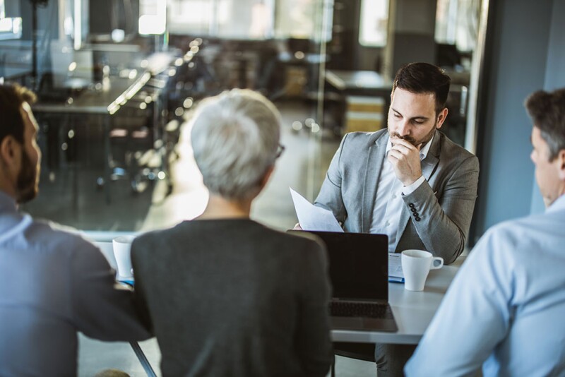 Thoughtful male candidate reading his resume on a job interview in the office.