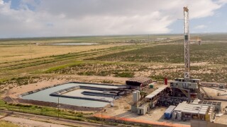 Fracking Drilling Rig Evening Shot under dramatic Sky in West Texas with Settling Ponds on the Prairie