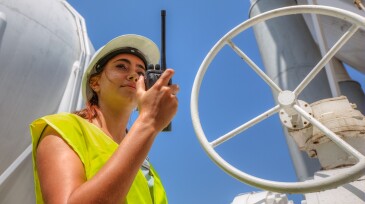 Business woman in a refinery talking on radio