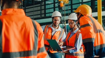 Team of industrial engineers meeting analyze machinery blueprints consult project on laptop in manufacturing factory. Engineering and sustainable production plant.
