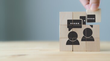 Consumer feedback concept.  Customer satisfaction evaluation to improve and develop product and service. Customer centric. Hand puts wooden cubes with "feedback" icon on grey background ,copy space.