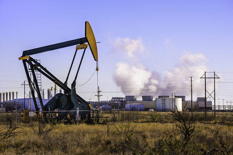 A pumpjack (oil derrick) and oil refinery in Seminole, West Texas.