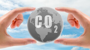 CO2 capture concept. Human hand holding CO2 in globe map on blue sky. Carbon capture and storage technology concept. Greenhouse gas. Carbon dioxide gas global air climate pollution. Environment issue.