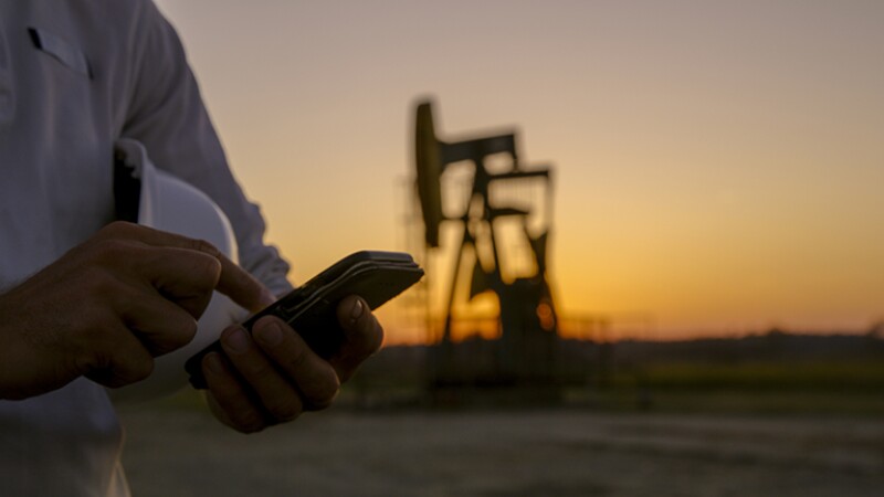 Close up of smart phone, drill rig in background