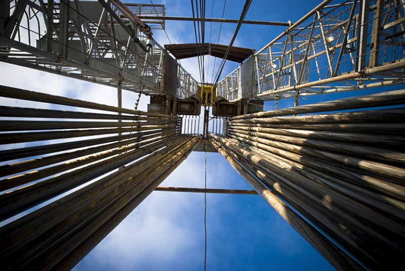 View looking upward at a drilling rig with a full loaded pipe rack.