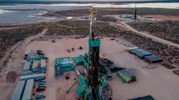 Drone captures a breathtaking sunset over the Permian Basin, showcasing an oil rig drilling and fracking for oil, amidst the vastness of the landscape