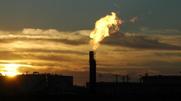 Industrial plant with fuel bowsers and gas flare into sky