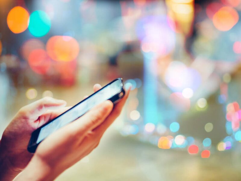 hand using cellphone against colorful background