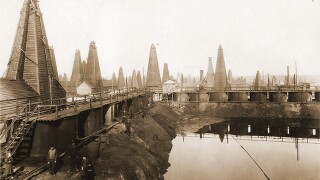 Cisterns reflect off crude oil and waste products captured in a pit adjacent to production wells in the Balakhani oil field in Baku, 1900–1917.