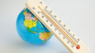 Globe and wooden eco-friendly thermometer on a white background. Temperature in Celsius and Faradays. Concept of climate change and global warming. Copy space. Selective focus.